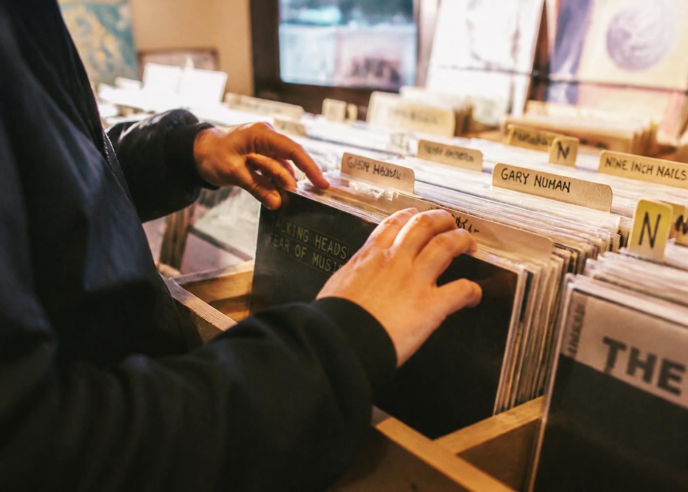 Hands flipping through vinyl records in a record store crate